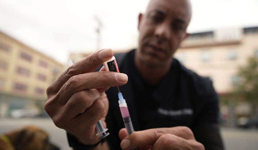 A doctor prepares a rabies vaccine. (AP Photo/Damian Dovarganes)