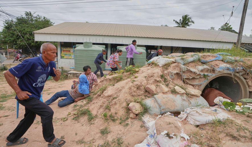 Village security volunteers and resident run into shelter while the blasts sounded too close in Buriram province, Thailand, Friday, Dec. 12, 2025, following renewed border conflict between Thailand and Cambodia. (AP Photo/Sakchai Lalit)