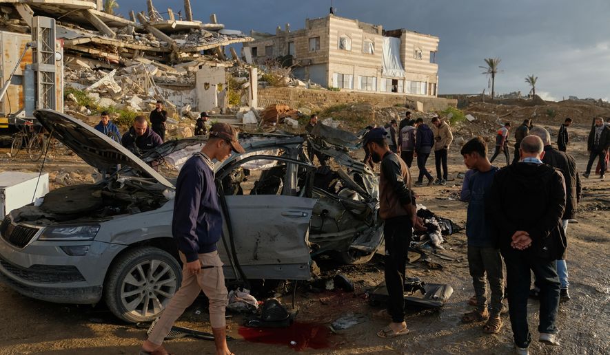 Palestinians looks at a destroyed car following an Israeli strike in Gaza City, Saturday, Dec. 13, 2025. (AP Photo/Jehad Alshrafi)