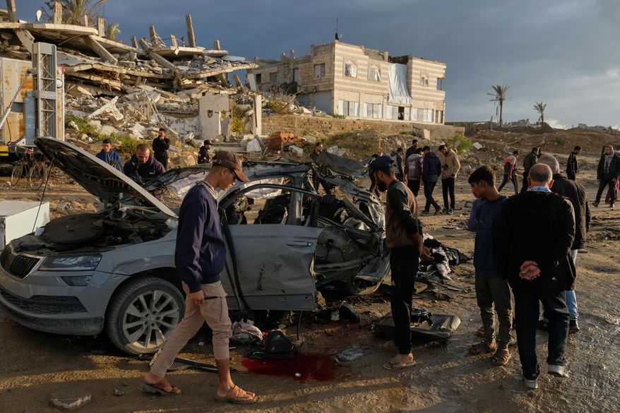 Palestinians looks at a destroyed car following an Israeli strike in Gaza City, Saturday, Dec. 13, 2025. (AP Photo/Jehad Alshrafi)