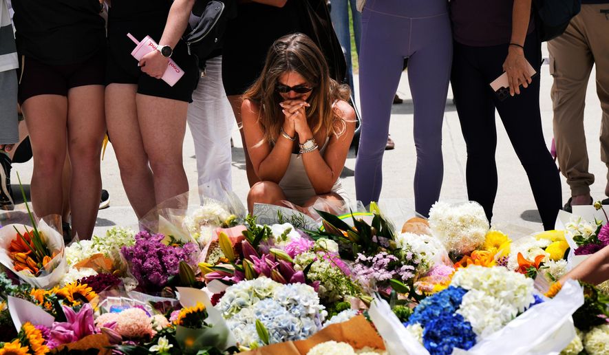 A woman kneels and prays at a flower memorial to shooting victims outside the Bondi Pavilion at Sydney's Bondi Beach, Monday, Dec. 15, 2025, a day after a shooting. (AP Photo/Mark Baker)