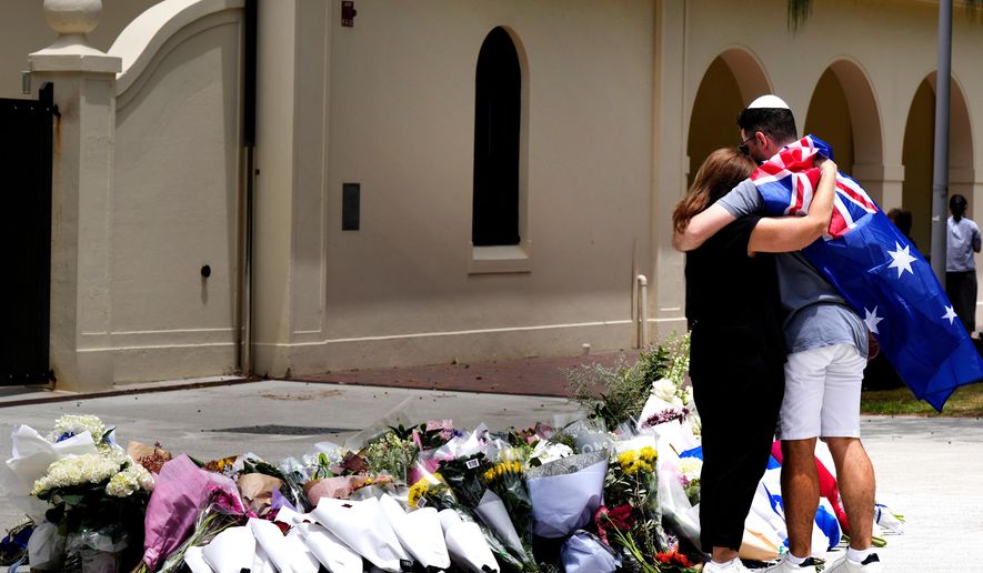 A couple lay flowers at a tribute to shooting victims outside the Bondi Pavilion at Sydney's Bondi Beach, Monday, Dec. 15, 2025, a day after a shooting. (AP Photo/Mark Baker)