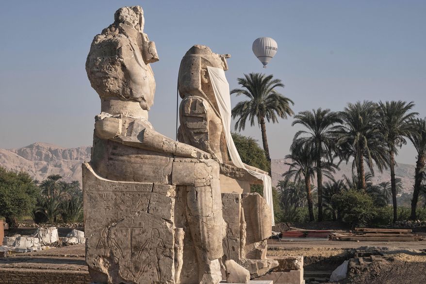 A hot air ballon flys over the assembly of two giant alabaster statues for Pharoah Amenhotep III, before the official opening, in the southern city of Luxor, Egypt, Sunday, Dec. 14, 2025. (AP Photo/Amr Nabil)