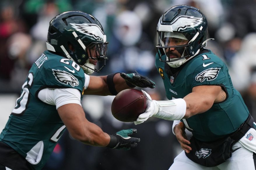 Philadelphia Eagles quarterback Jalen Hurts (1) hands off the ball to Philadelphia Eagles running back Saquon Barkley, left, during the first half of an NFL football game against the Las Vegas Raiders on Sunday, Dec. 14, 2025, in Philadelphia. (AP Photo/Matt Slocum)