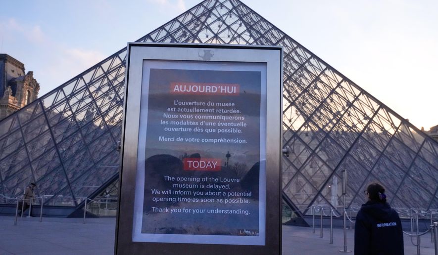 A board advises opening delays outside the pyramid of the Louvre museum as workers at the Louvre will vote to go on strike or continue talks with the government after months of mounting pressure on the world's most visited museum, Monday, Dec. 15, 2025 in Paris. (AP Photo/Michel Euler)