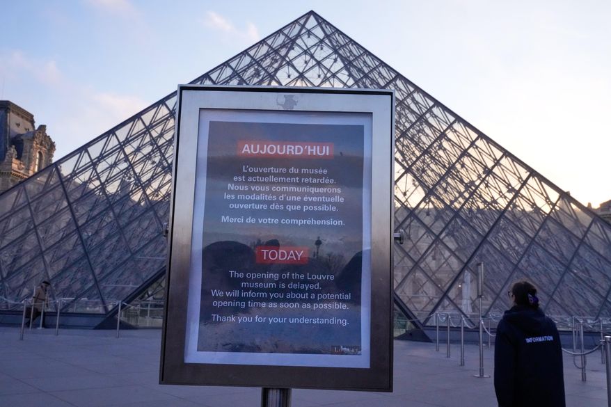 A board advises opening delays outside the pyramid of the Louvre museum as workers at the Louvre will vote to go on strike or continue talks with the government after months of mounting pressure on the world's most visited museum, Monday, Dec. 15, 2025 in Paris. (AP Photo/Michel Euler)