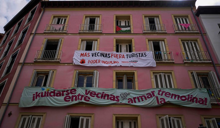 FILE - Banners against tourist holiday rentals hang on the facade of a building in downtown Madrid, Spain, Tuesday, June 3, 2025. The writing in Spanish reads: "More neighbors, fewer tourists. Tenant power," and "Looking out for each other as neighbors, stirring things up." (AP Photo/Manu Fernandez)