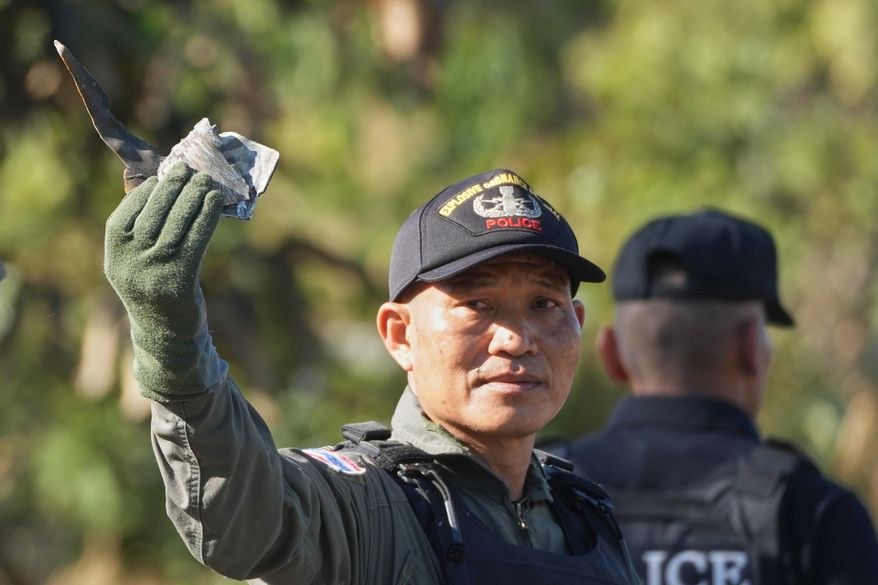 A member of a Thai Explosive Ordnance Disposal team shows pieces of shrapnel as they inspect the site of a rocket attack during clashes between Thai and Cambodian soldiers in Kantharalak district of Sisaket province, Thailand, Monday, Dec. 15, 2025. (AP Photo/Sakchai Lalit)