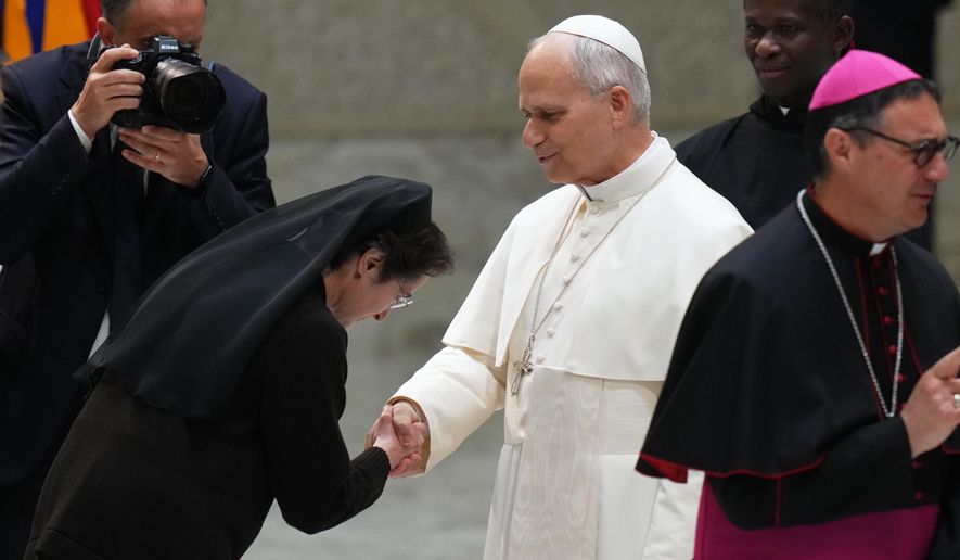 Pope Leo XIV, center, shakes hands with Sister Raffaella Petrini, President of the Vatican City State at the end of an audience with donors of the Christmas tree and nativity scene set up in St. Peter's Square, in the Paul VI Hall, at the Vatican, Monday, Dec. 15, 2025. (AP Photo/Alessandra Tarantino)
