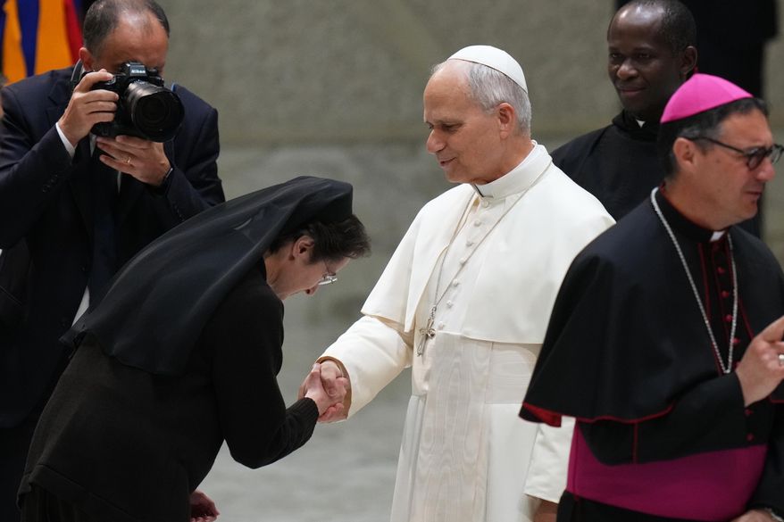 Pope Leo XIV, center, shakes hands with Sister Raffaella Petrini, President of the Vatican City State at the end of an audience with donors of the Christmas tree and nativity scene set up in St. Peter's Square, in the Paul VI Hall, at the Vatican, Monday, Dec. 15, 2025. (AP Photo/Alessandra Tarantino)
