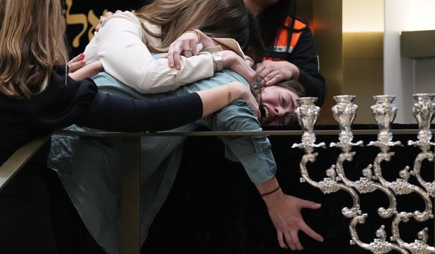 Family react at the coffin of Rabbi Eli Schlanger, a victim in the Bondi Beach mass shooting, during his funeral at a synagogue in Bondi on Wednesday, Dec. 17, 2025, in Sydney, Australia. (AP Photo/Mark Baker, Pool)