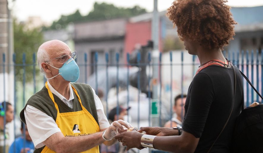 Priest Julio Lancellotti hands food to a homeless person in Sao Paulo, Brazil, April 3, 2020. (AP Photo/Andre Penner, File)