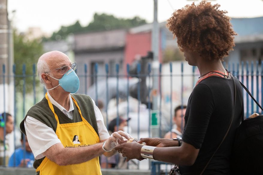 Priest Julio Lancellotti hands food to a homeless person in Sao Paulo, Brazil, April 3, 2020. (AP Photo/Andre Penner, File)
