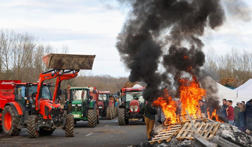 French farmers gather around a fire as they block the highway near Urt, southwestern France, to protest against a mass cull of cows ordered to contain the spread of a skin disease, Monday Dec. 15, 2025. (AP Photo/Nicolas Mollo, File)