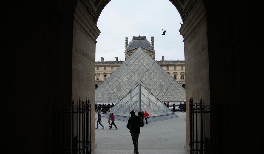 People wait at the entrance of the Louvre museum as employees were set to vote on whether to extend a strike that shut the world's most visited museum, as unions protest chronic understaffing, building deterioration and recent management decisions Wednesday, Dec. 17, 2025 in Paris. (AP Photo/Christophe Ena)