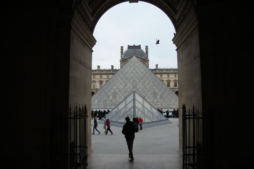 People wait at the entrance of the Louvre museum as employees were set to vote on whether to extend a strike that shut the world's most visited museum, as unions protest chronic understaffing, building deterioration and recent management decisions Wednesday, Dec. 17, 2025 in Paris. (AP Photo/Christophe Ena)