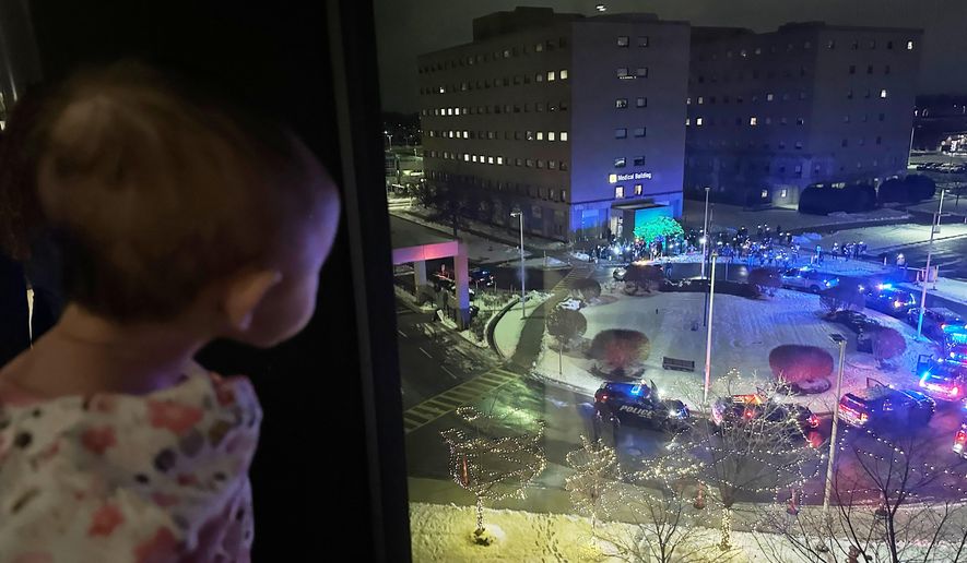 A hospitalized child looks out the window at volunteers who are shining lights up into the pediatric wing of Corewell Health Children's during a Moonbeams for Sweet Dreams event Wednesday, Dec. 10, 2025, in Royal Oak, Mich. (AP Photo/Mike Householder)