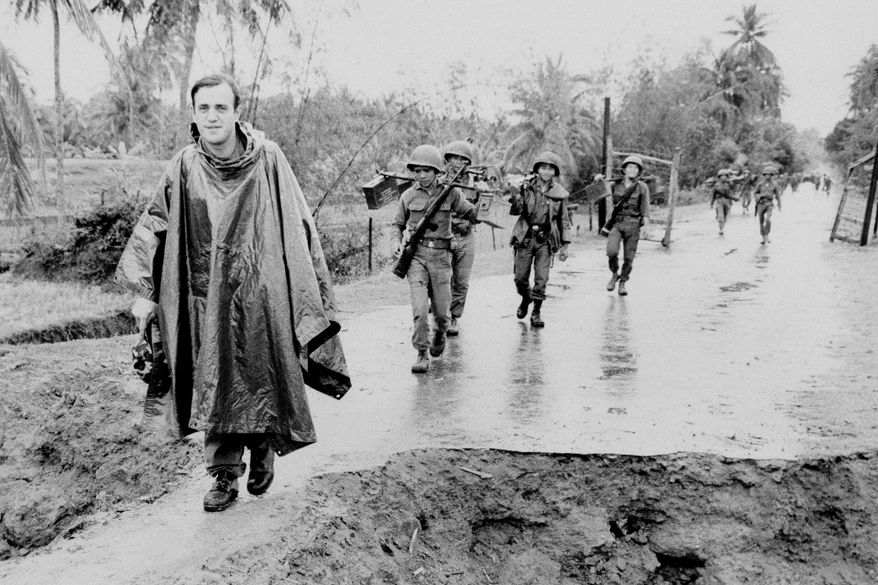 Associated Press correspondent Peter Arnett, left, marches with Vietnamese troops in Vietnam, Nov. 11, 1965. (AP Photo, File)