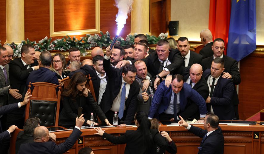Belind Kellici, a Member of Parliament representing the Democratic Party, holds a flare during tensions between the ruling Socialist Party and the opposition during a parliament session in Tirana, Albania, Thursday, Dec. 18, 2025. (AP Photo)