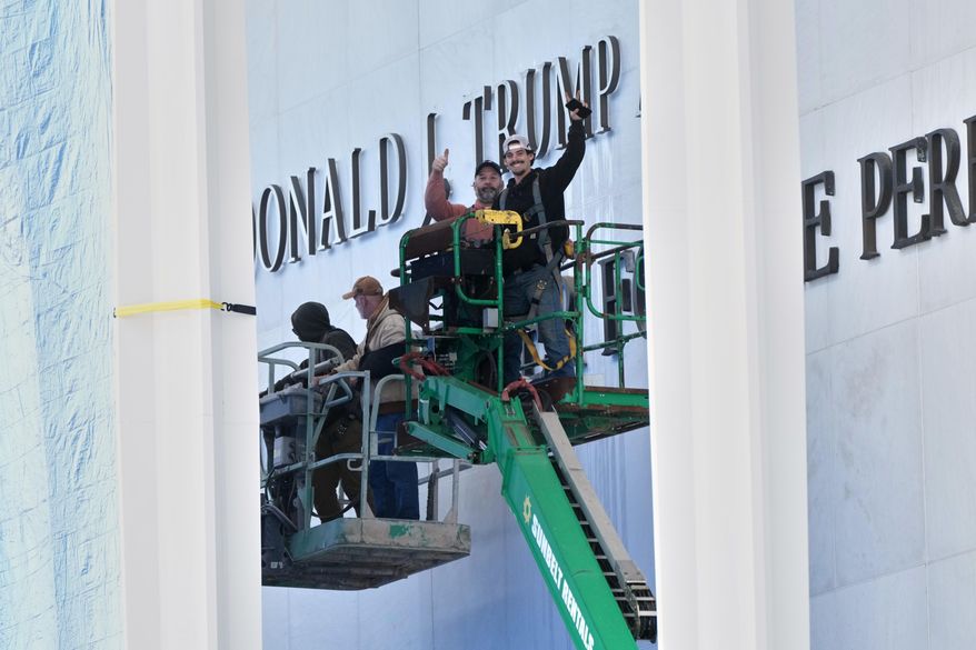 Workers install Donald J. Trump above the current signage on the Kennedy Center on Friday, Dec. 19, 2025, in Washington. (AP Photo/Jacquelyn Martin)