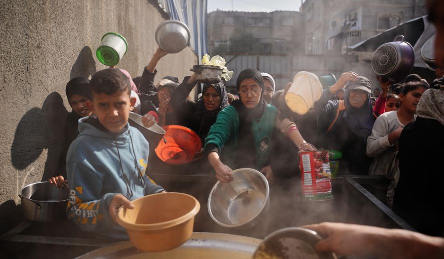 Palestinian women struggle to receive donated food at a community kitchen in Nuseirat, central Gaza Strip, Wednesday, Dec. 17, 2025. (AP Photo/Abdel Kareem Hana, File)