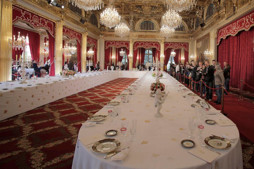 Visitors view a table dressed with plates and glasses for official dinners at the Elysee Palace in Paris, Saturday, Sept. 15, 2012. France's national buildings and administrations were opened to the public for Heritage Days weekend. (AP Photo/Christophe Ena, File)