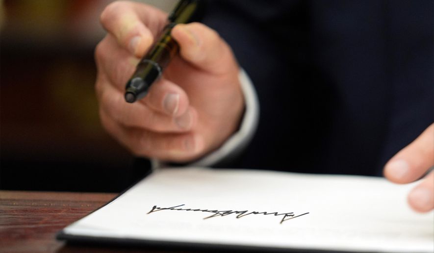 FILE - President Donald Trump signs executive orders in the Oval Office of the White House, Monday, Jan. 20, 2025, in Washington. (AP Photo/Evan Vucci, File)