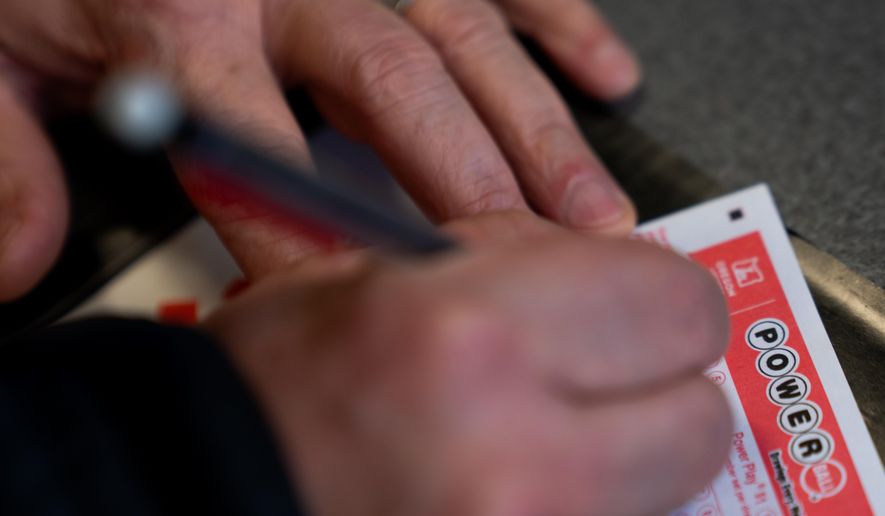 A person fills out a Powerball lottery ticket on Monday, Dec. 22, 2025, in Portland, Ore. (AP Photo/Jenny Kane)