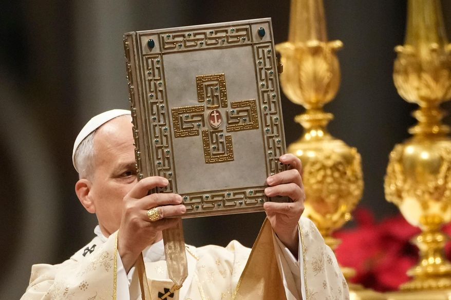 Pope Leo XIV holds up the book of the Gospel during the Christmas Day Mass at the St. Peter's Basilica at the Vatican, Thursday, Dec. 25, 2025. (AP Photo/Gregorio Borgia)