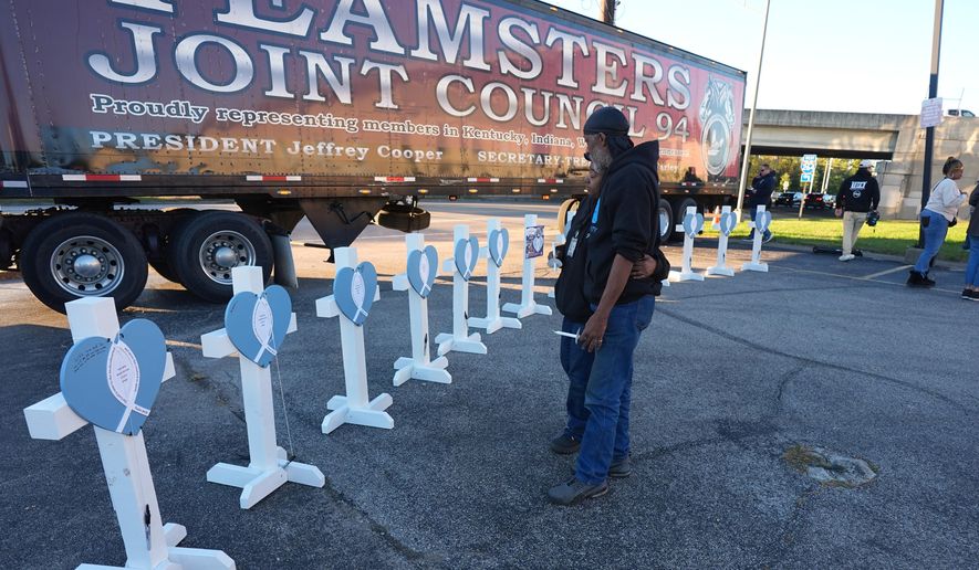 Allen Wilson, right, hugs an attendee after writing on crosses for victims during a vigil Thursday, Nov. 6, 2025, in Louisville, Ky., after a UPS plane crashed at Louisville Muhammad Ali International Airport. (AP Photo/Darron Cummings, File)