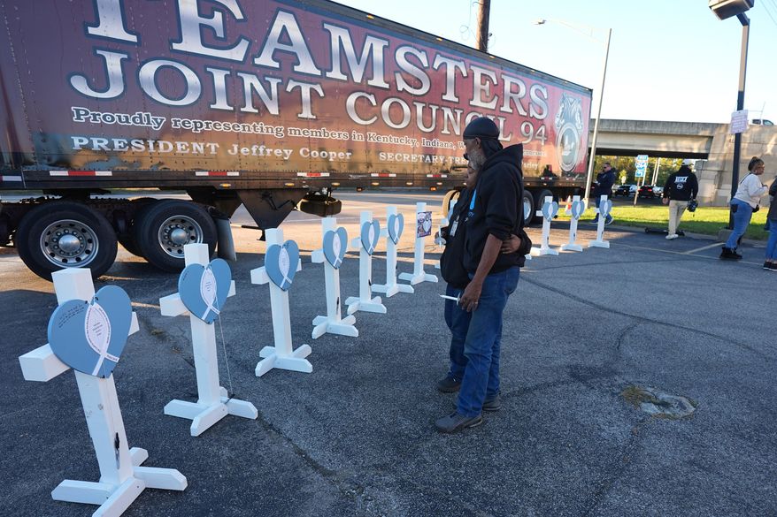 Allen Wilson, right, hugs an attendee after writing on crosses for victims during a vigil Thursday, Nov. 6, 2025, in Louisville, Ky., after a UPS plane crashed at Louisville Muhammad Ali International Airport. (AP Photo/Darron Cummings, File)
