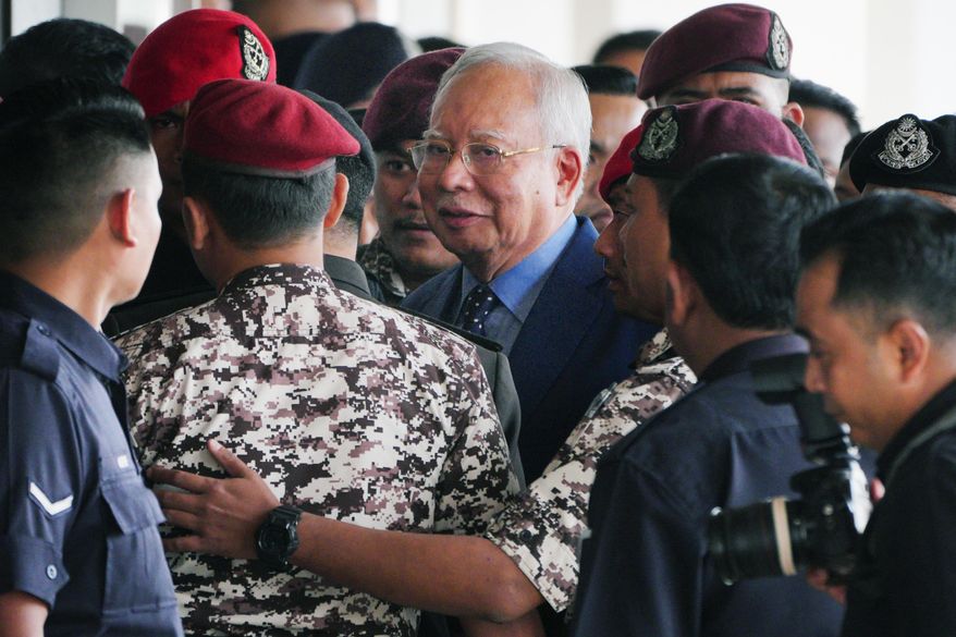 FILE - Malaysian former Prime Minister Najib Razak, center, is escorted by prison officers on his arrival at the Kuala Lumpur High Court complex in Kuala Lumpur, Malaysia, Oct. 30, 2024. (AP Photo/Vincent Thian, File)