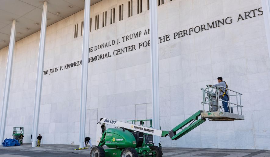 Workers add President Donald Trump's name to the John F. Kennedy Memorial Center for the Performing Arts, after a Trump-appointed board voted to rename the institution, in Washington, Friday, Dec. 19, 2025. (AP Photo/J. Scott Applewhite)