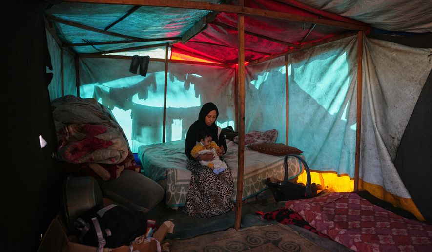 Shaimaa Wadi, 25, sits with her 1-year-old daughter Tala, inside their tent in a makeshift camp for displaced Palestinians in Deir al-Balah, central Gaza Strip, Saturday, Dec. 27, 2025. (AP Photo/Abdel Kareem Hana)