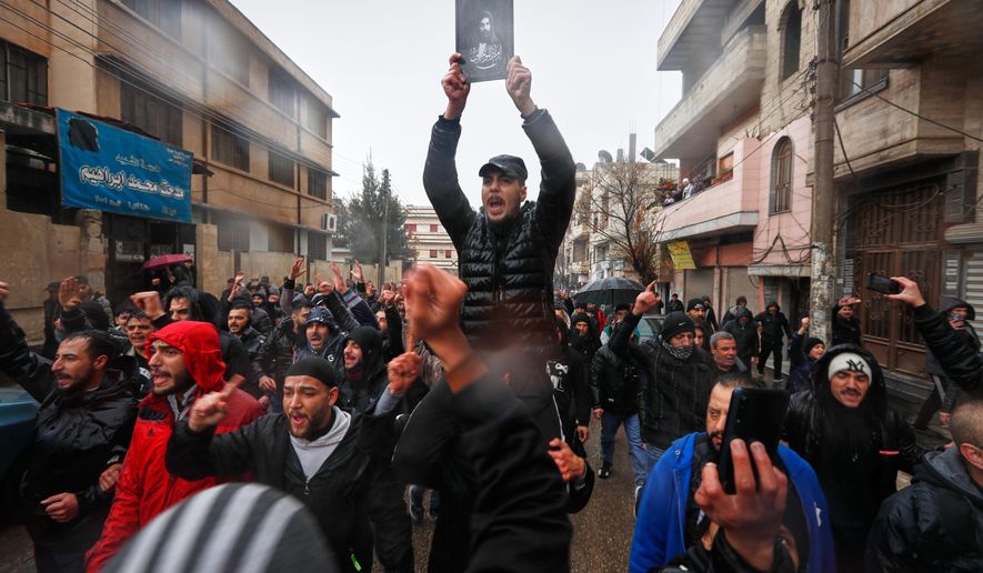 A man holds an imaginary depiction of Ali ibn Abi Talib, the cousin and son-in-law of the Prophet Muhammad who is revered by Syria's Alawite community, during the funeral of victims of an attack a day earlier at the Imam Ali bin Abi Talib Mosque in the predominantly Alawite Wadi al-Dhahab neighborhood of Homs, Syria, Saturday, Dec. 27, 2025. (AP Photo/Omar Sanadiki)