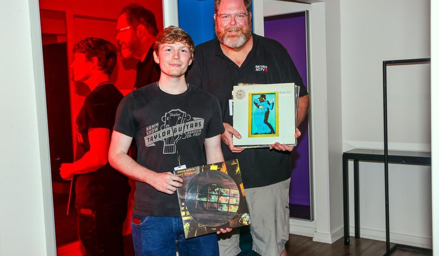 This photo provided by Mel D. Cole shows Carson Bispels, left, posing for a photo with his father, Martin Bispels, who recently started Retroactv, a company that sells rock merchandise dating back to the 1960s and 1970s, on Aug. 1, 2025, in Asbury Park, N.J. (Mel D. Cole via AP)
