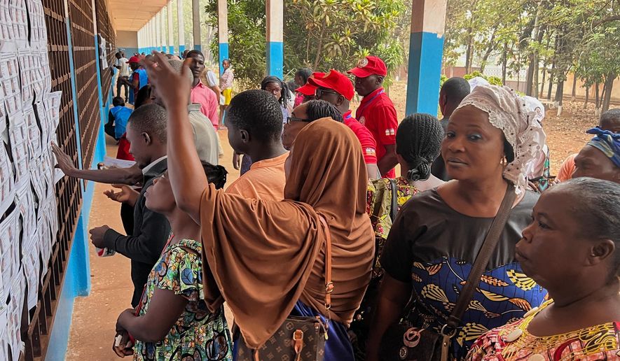 Voters look for their names on a registration list at a polling station during the presidential election in Bangui, Central African Republic, Sunday, Dec. 28, 2025. (AP Photo/Jean-Fernand Koena)