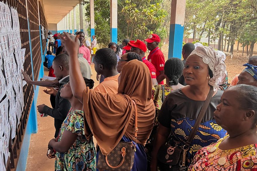 Voters look for their names on a registration list at a polling station during the presidential election in Bangui, Central African Republic, Sunday, Dec. 28, 2025. (AP Photo/Jean-Fernand Koena)