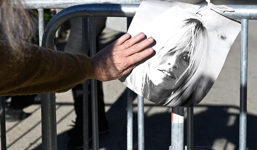 A woman touches a poster showing actor Brigitte Bardo near her home in Saint-Tropez, southern France, Sunday, Dec. 28, 2025 after the French 1960s sex symbol who became one of the greatest screen sirens of the 20th century and later a militant animal rights activist and far-right supporter, has died. She was 91. (AP Photo/Philippe Magoni)