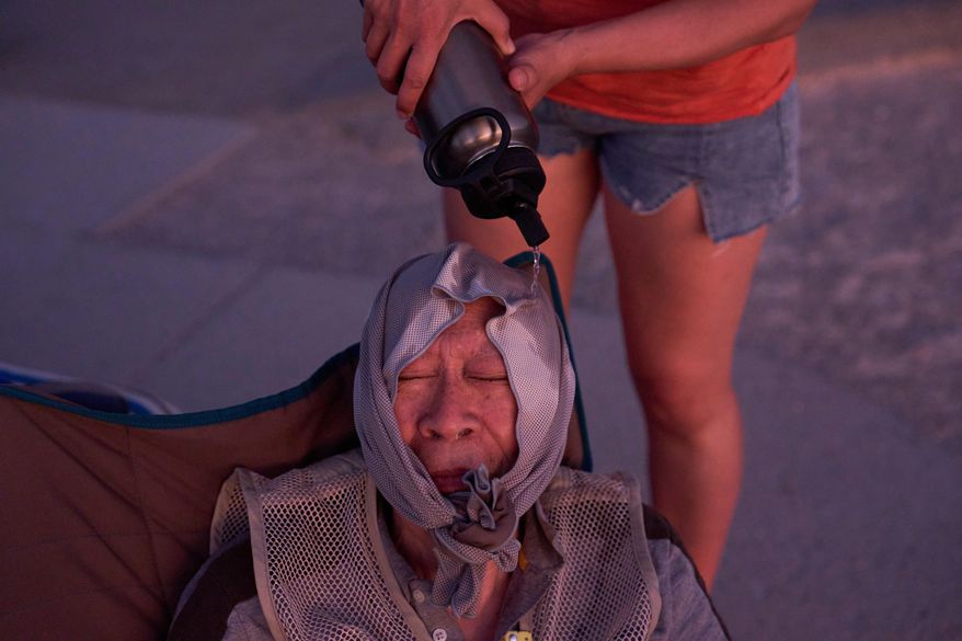 FILE - Grace Chyuwei pours water on Joe Chyuwei to help with the heat Aug. 3, 2025, in Death Valley National Park, Calif. (AP Photo/John Locher, File)