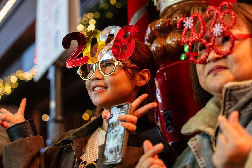 People pose for photographs at Lan Kwai Fong to celebrate the start of 2026 in the Central district of Hong Kong, on Wednesday, Dec. 31, 2025. (AP Photo/Chan Long Hei)