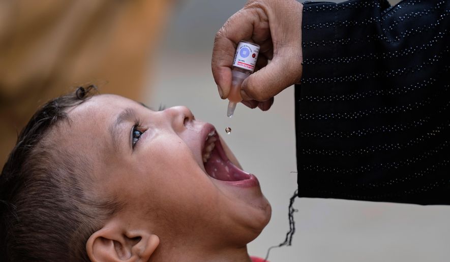 A health worker administers a polio vaccine to a child at a neighbourhood in Karachi, Pakistan, Monday, Monday, Dec. 15, 2025. (AP Photo/Fareed Khan)
