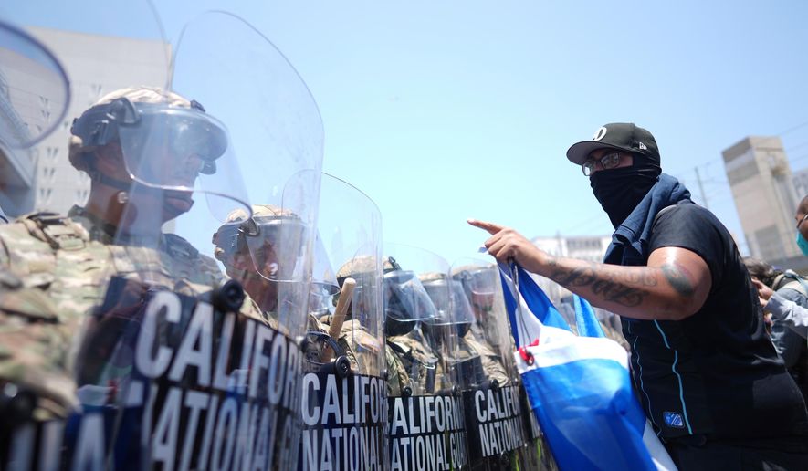 A protester confronts a line of U.S. National Guard members in the Metropolitan Detention Center of downtown Los Angeles, Sunday, June 8, 2025. (AP Photo/Eric Thayer, File)