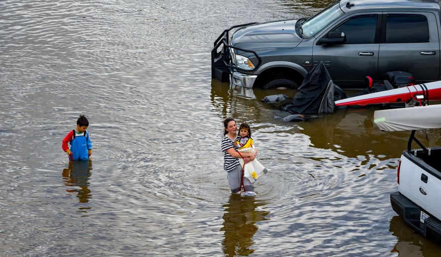 People wade through an rv park flooded by the "King Tides", occurring when the sun, moon and Earth align, causing a stronger gravitational pull Saturday, Jan. 3, 2026, near Corte Madera in Marin County, Calif. (AP Photo/Ethan Swope)