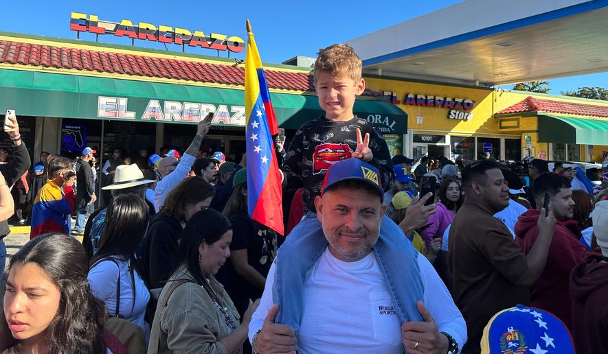 Lorenzo Coppola, 47, and his son Valentino join others to celebrate the news of Venezuelan President Nicolás Maduro capture in Doral, Fla., on Saturday, Jan. 3, 2026. (AP Photo/Vanessa Alvarez)