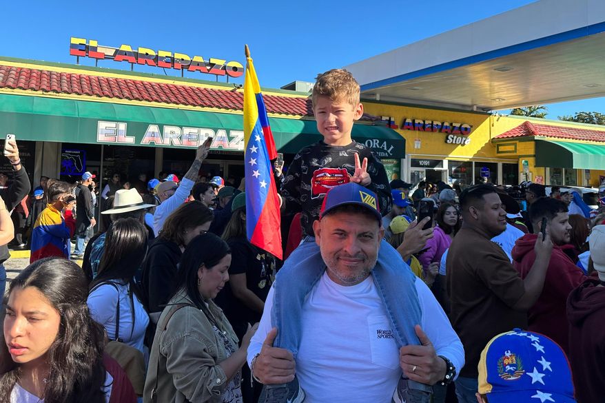 Lorenzo Coppola, 47, and his son Valentino join others to celebrate the news of Venezuelan President Nicolás Maduro capture in Doral, Fla., on Saturday, Jan. 3, 2026. (AP Photo/Vanessa Alvarez)