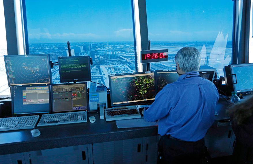 FILE - In this Sept. 4, 2013 photo, an air traffic controller works at computer screens and a digital clock showing Coordinated Universal Time (UTC), or Zulu time, is seen in this view looking eastward from the control tower at Los Angeles International Airport (LAX). (AP Photo/Reed Saxon, File)