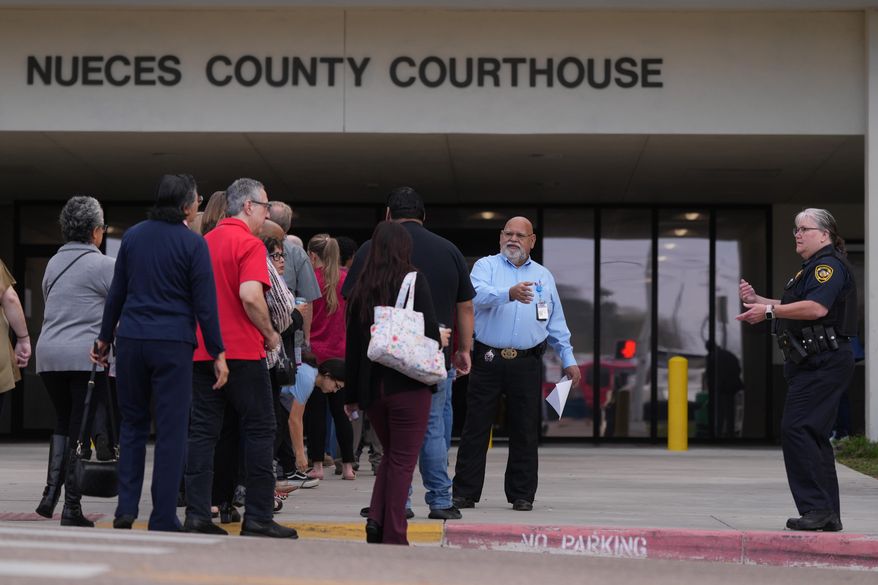 Officials monitor a line outside the Nueces County Courthouse in Corpus Christi, Texas, where jury selection begins for the State of Texas v. Adrian Gonzales, a former police officer for schools in Uvalde, Monday, Jan. 5, 2026. (AP Photo/Eric Gay)