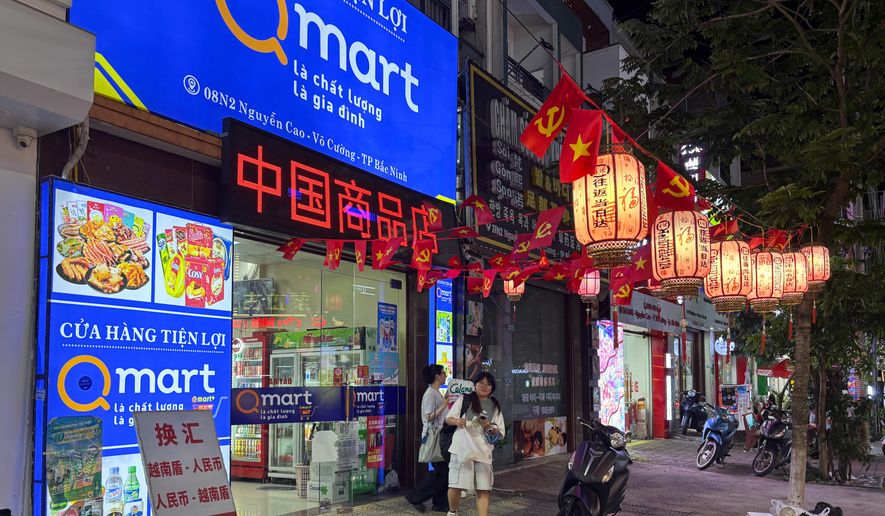 Two Vietnamese girls come out of a Vietnamese convenience store with signboard including Chinese characters in downtown Bac Ninh, Vietnam, Nov. 3, 2025. (AP Photo/Vincent Thian)
