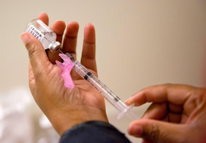 FILE - In this Feb. 7, 2018 file photo, a nurse prepares a flu shot at the Salvation Army in Atlanta. (AP Photo/David Goldman, File)